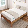Wooden bed with white mattress and beige pillows in a modern bedroom setting.