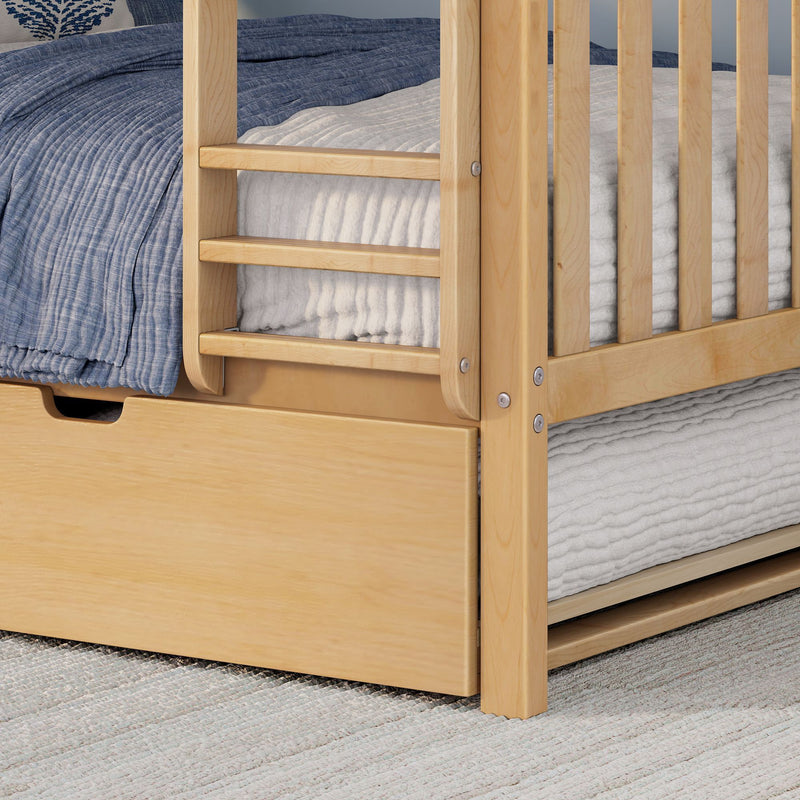 Solid natural wood bunk bed ladder and safety guardrail with blue quilted bedding and pull-out underbed storage drawer on woven rug