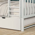 Close-up of white wooden bunk bed ladder and safety rails with beige textured bedding, tassel throw and built-in under-bed storage drawer on a natural jute rug