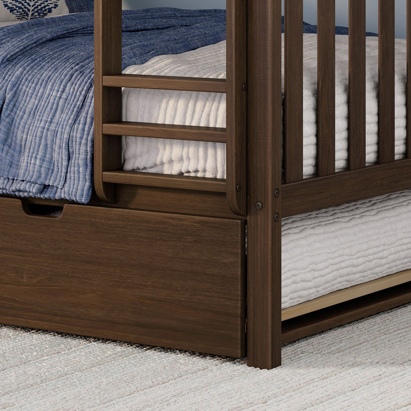 Close-up of dark wood bunk bed corner with slatted frame, under-bed storage drawer, textured white mattress and blue quilted bedding