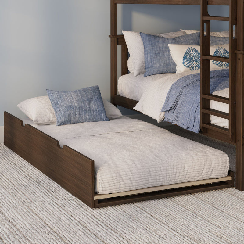 Wooden bunk bed with pull-out trundle, white quilted bedding and blue decorative pillows on a textured rug