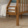 Wooden bunk bed ladder close-up with slatted oak frame, gray bedding and fringed throw on textured jute rug — modern farmhouse bedroom detail