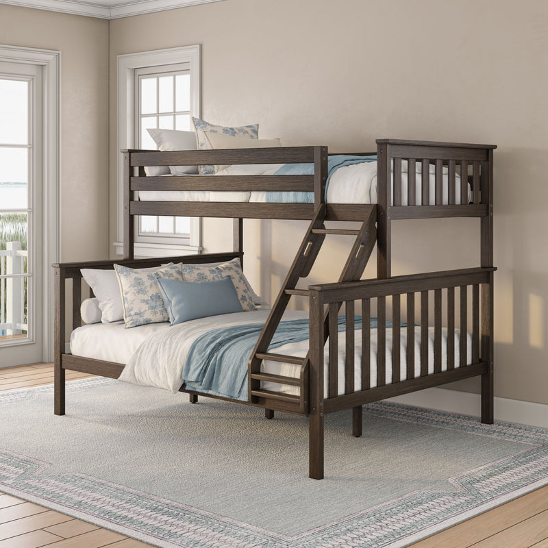 Dark wood twin-over-full bunk bed with ladder in a coastal-style bedroom, layered blue and floral pillows, neutral walls and sunlight from windows