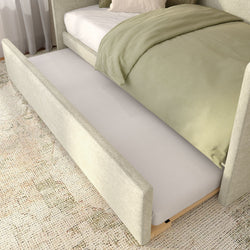 Beige upholstered bed with pull-out trundle mattress, sage green duvet and textured rug in a modern neutral bedroom