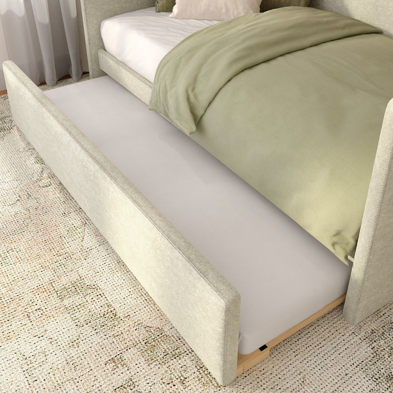 Beige upholstered bed with pull-out trundle mattress, sage green duvet and textured rug in a modern neutral bedroom