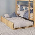 Light wood bunk bed with pull-out trundle, neutral quilted bedding and blue decorative pillows in a cozy modern bedroom.