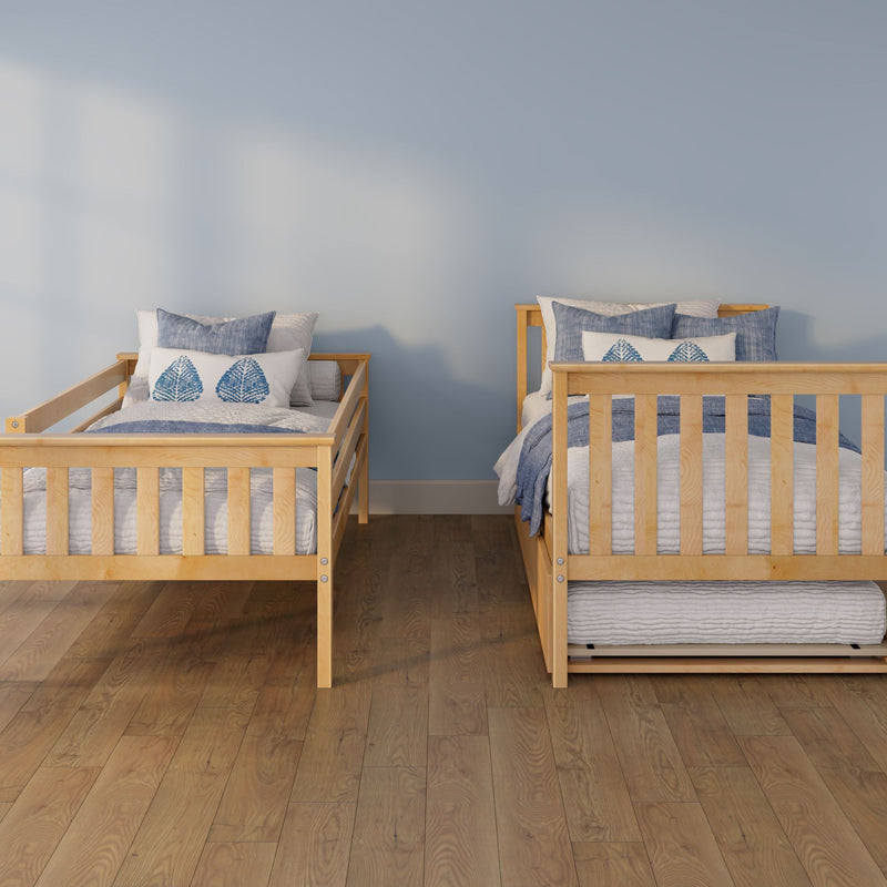Wooden twin beds with blue and white leaf-pattern pillows and blue bedding against a soft blue wall on hardwood floor, coastal kids bedroom