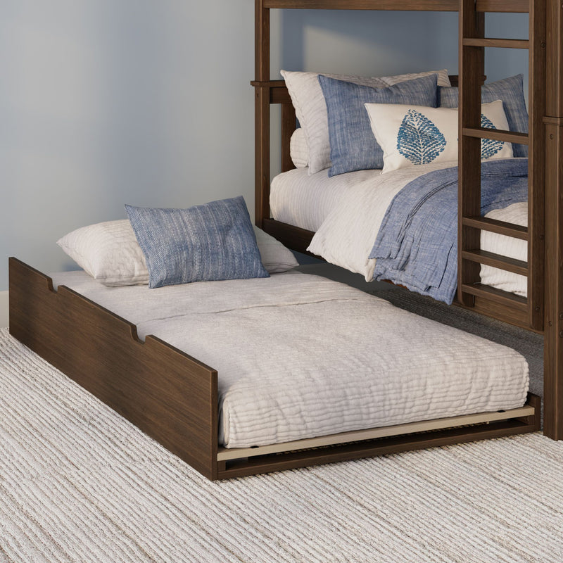 Wooden bunk bed with blue and white bedding and leaf-print accent pillow over pull-out trundle on textured rug