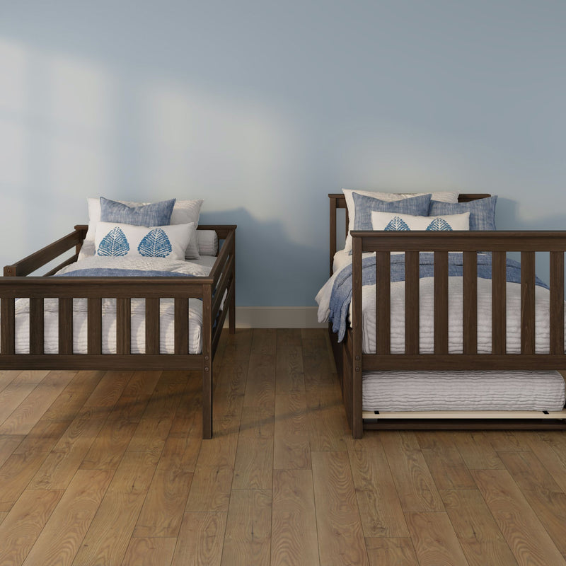 Two wooden twin beds with blue leaf-print pillows and white quilts on a hardwood floor against a light blue bedroom wall