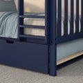 Close-up of a navy blue wooden bunk bed frame with ladder, under-bed storage drawer and light-blue textured bedding in a modern kids' bedroom