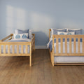 Twin natural wood beds with blue and white coastal bedding in a minimalist kids' bedroom with a light blue wall and hardwood floor