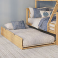 Light wood bunk bed with pull-out trundle, neutral quilted bedding and blue decorative pillows in a coastal-style kids' bedroom