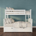 White wooden bunk bed with ladder, beige bedding and pillows, under-bed storage drawer against teal textured wall on dark hardwood floor
