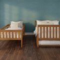 Two wooden twin beds with white bedding and striped pillows against a teal textured wall, dark hardwood floor and minimalist bedroom interior