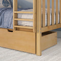 Close-up of a light maple solid-wood bunk bed frame with ladder rails, built-in underbed storage drawer and blue quilted bedding on a textured rug