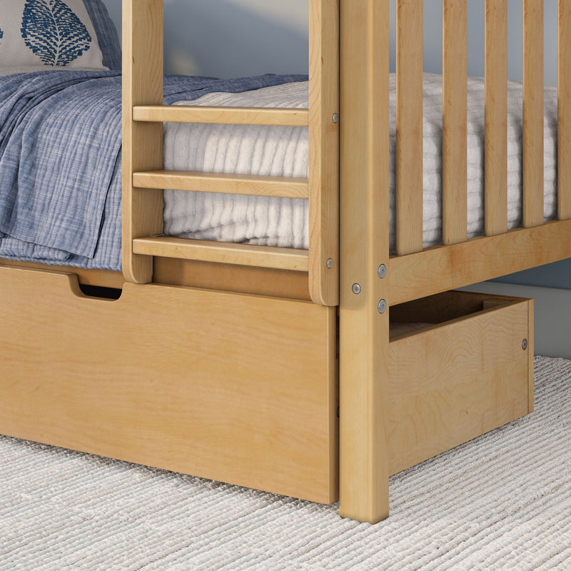 Close-up of a light maple solid-wood bunk bed frame with ladder rails, built-in underbed storage drawer and blue quilted bedding on a textured rug