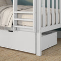 Close-up of modern white wooden bunk bed with safety rails and ladder, under-bed storage drawer, beige linen bedding and woven jute rug