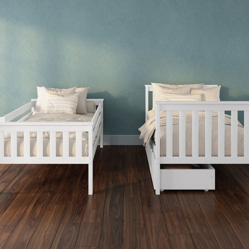 Two white wooden twin beds with beige bedding and striped pillows in a kids' bedroom with teal textured wall and dark hardwood floor