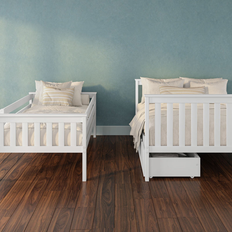 Nursery with white wooden twin beds, neutral beige bedding and under-bed storage against a teal textured wall on dark hardwood floor
