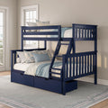 Navy blue wooden bunk bed with ladder and built-in storage drawers, styled with white and blue linens and floral pillows in a bright coastal bedroom