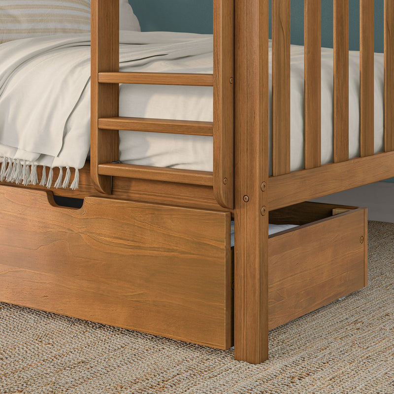 Close-up of solid oak bunk bed corner with slatted guardrail and ladder, built-in storage drawer, neutral bedding and tasseled throw on woven rug