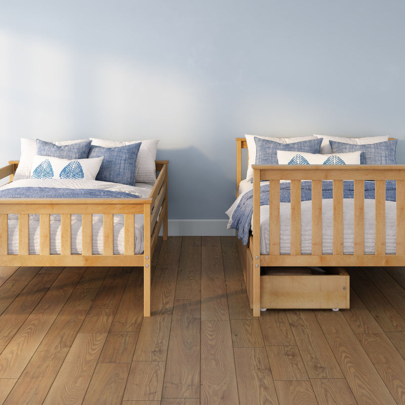 Two wooden twin beds with blue-and-white bedding and leaf-print pillows in a coastal-style bedroom with a light blue wall and hardwood floor