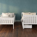 Two white wooden twin beds with beige pillows and striped cushions, under-bed storage drawer, teal textured accent wall and dark hardwood floor