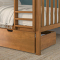 Close-up of wooden bunk bed with ladder and built-in underbed storage drawer, beige linen bedding and woven jute rug