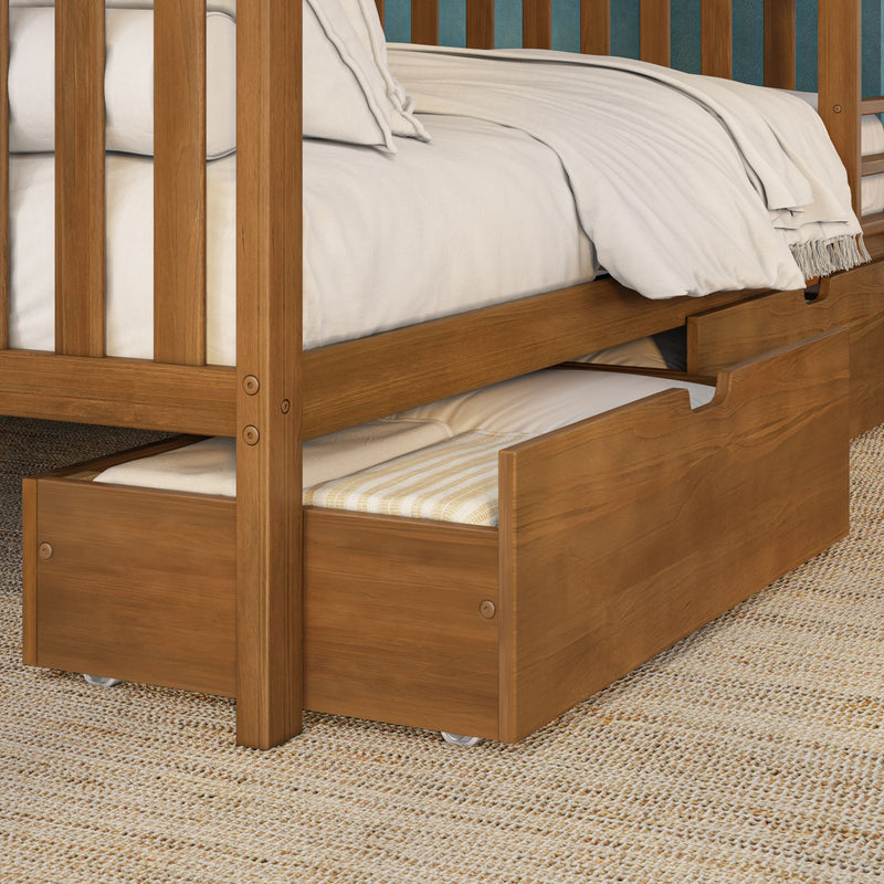Solid wood bunk bed with pull-out trundle drawer, white bedding and folded blanket, warm wood finish on woven jute rug