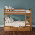 Solid wood bunk bed with under-bed storage drawers, white bedding and pillows against a teal textured wall on dark hardwood floor