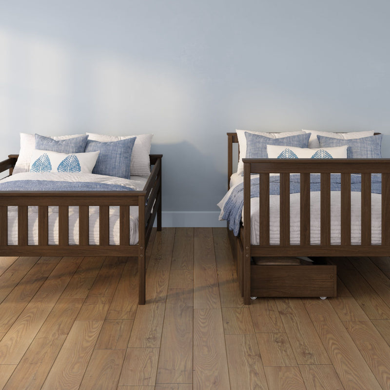 Two dark wood twin beds with blue and white bedding and pillows against a pale blue wall on a hardwood floor, bedroom interior
