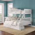 White wooden bunk bed with ladder and storage drawers in a coastal bedroom featuring a teal textured accent wall, large windows, layered neutral bedding and a natural jute rug on hardwood floors