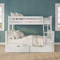 White wooden bunk bed with ladder and under-bed storage drawers, beige bedding and pillows against a teal accent wall in a children's bedroom