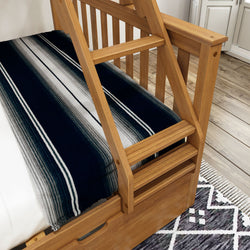 Wooden bunk bed with built-in ladder and black-and-white striped bedding on top mattress.
