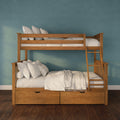 Natural wood twin-over-twin bunk bed with ladder and under-bed storage drawers, dressed in white linens and pillows against a teal blue textured wall.