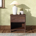 Wooden nightstand with white ceramic table lamp, two decorative vases and candle against a pale green textured wall
