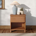 Minimalist bedroom decor: glossy light blue ceramic lamp with beige fabric shade on wooden nightstand beside a potted plant and candle