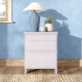 Blue ceramic table lamp with white shade on a light wood bedside table against a textured blue wall, accompanied by pottery vases and a candle — coastal bedroom decor.