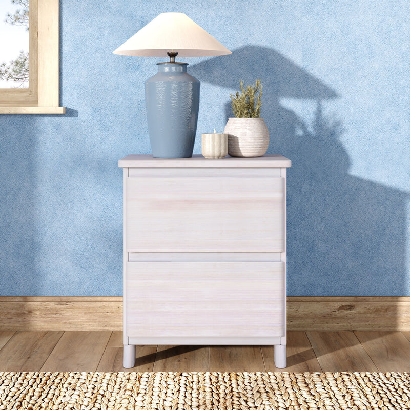 Blue ceramic table lamp with white shade on a light wood bedside table against a textured blue wall, accompanied by pottery vases and a candle — coastal bedroom decor.