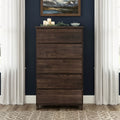 Tall dark walnut five-drawer dresser in modern bedroom with navy blue wall, white curtains, framed landscape art, decorative candles and wood floor rug
