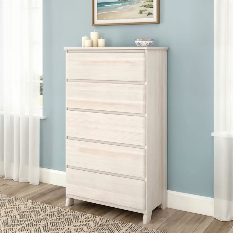 Whitewashed 5-drawer tall dresser chest for bedroom storage in a coastal-style room with blue wall, beach artwork, decorative candles and hardwood floor