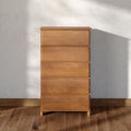 Tall light-oak dresser chest of drawers with minimalist design against a textured white wall on hardwood floor — modern bedroom storage