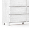 Close-up of a whitewashed wooden dresser lower corner with recessed drawer fronts and tapered mid-century style legs, modern farmhouse bedroom storage furniture