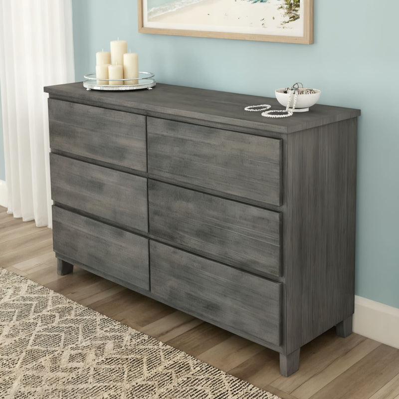 Gray wooden 6-drawer dresser with rustic finish in coastal bedroom, styled with candles and jewelry bowl — modern farmhouse bedroom storage