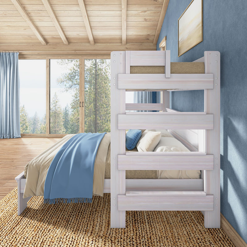 Whitewashed wooden bunk bed in a bright rustic bedroom with a blue throw blanket, woven jute rug and floor-to-ceiling windows overlooking a pine forest