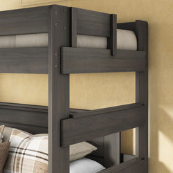 Gray stained solid wood bunk bed frame with safety guardrails and plaid accent pillows against a beige wall
