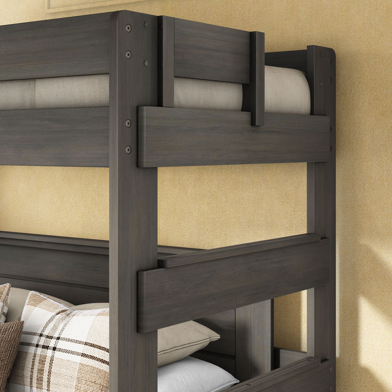 Gray stained solid wood bunk bed frame with safety guardrails and plaid accent pillows against a beige wall
