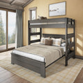 Gray wooden twin-over-full bunk bed in a cozy rustic bedroom with beige bedding, plaid throw pillows, large window showing forest view and area rug