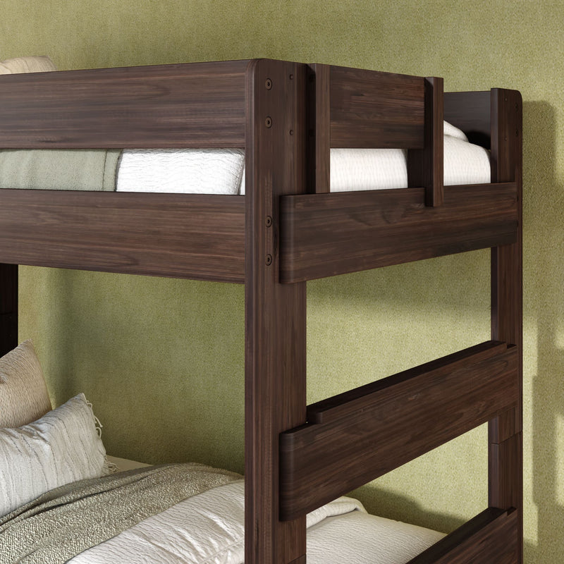 Close-up of dark walnut solid wood twin bunk bed with beige bedding and safety rails against a green bedroom wall