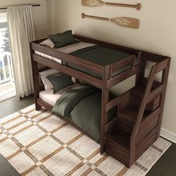 Wooden twin-over-twin bunk bed with built-in storage staircase in dark walnut finish, green bedding and pillows, rustic oar wall decor, cream curtains and patterned area rug in a bright kids' bedroom